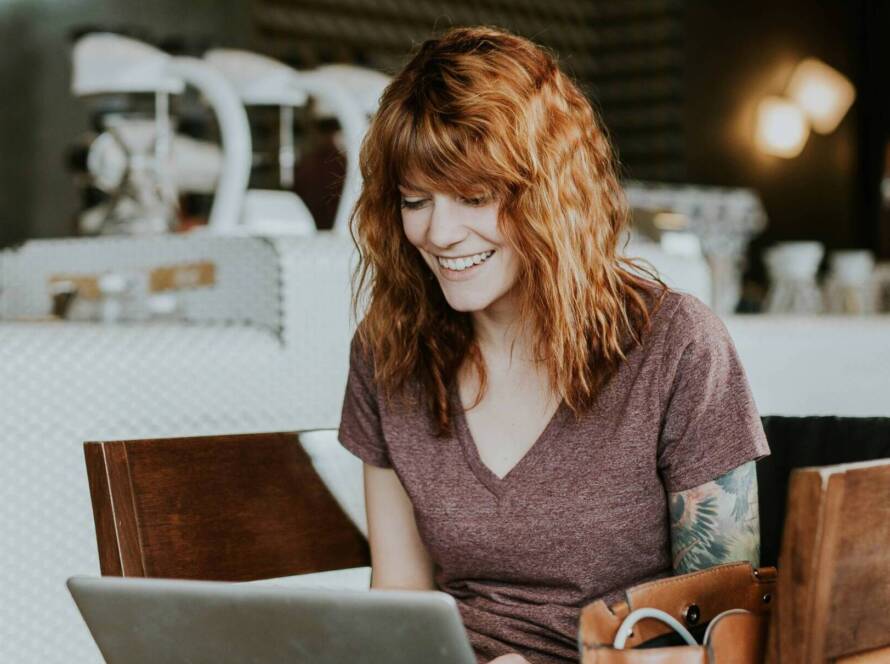 Smiling woman using laptop in cafe.