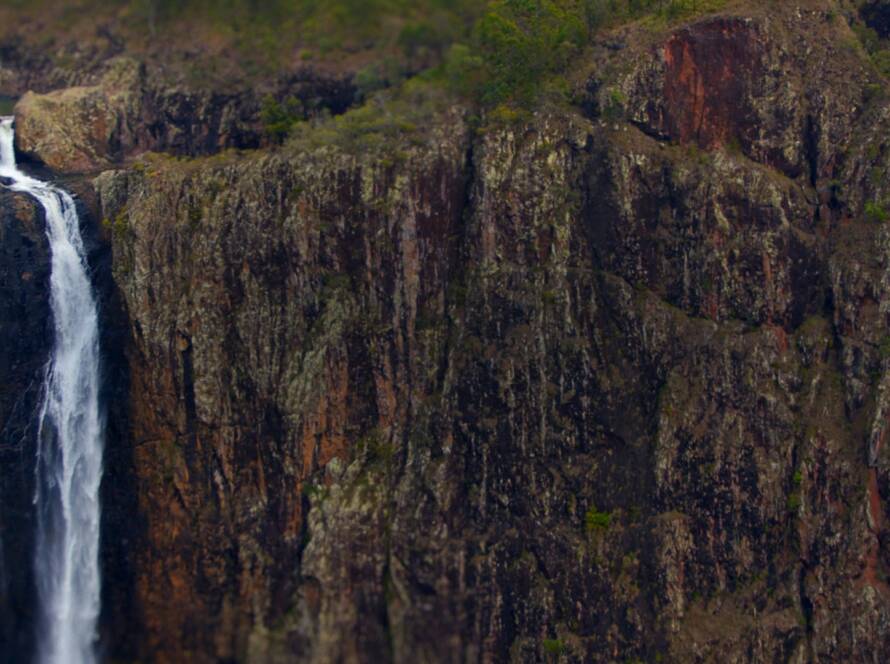 A large cliff with green vegetation on it.