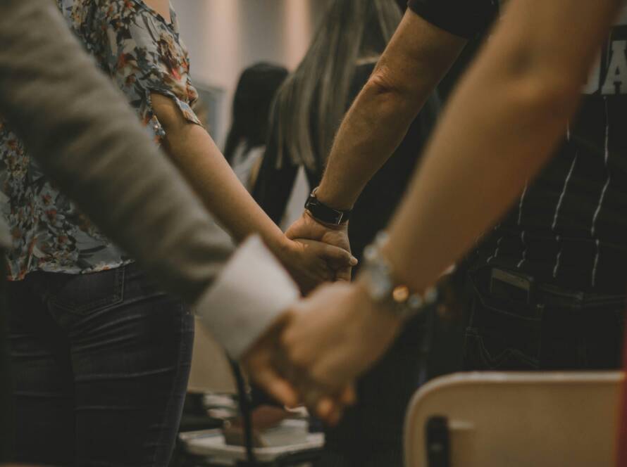 A group of people holding hands in a room.