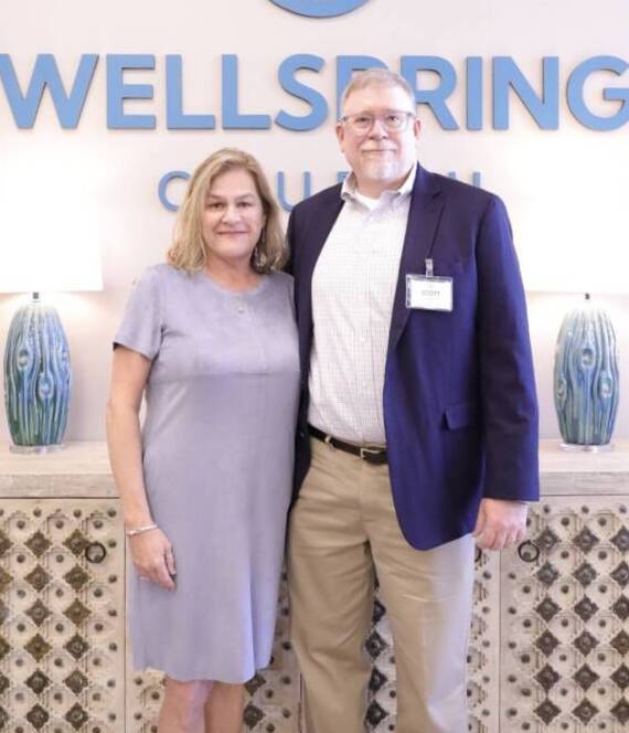 Two people standing in front of Wellspring sign.