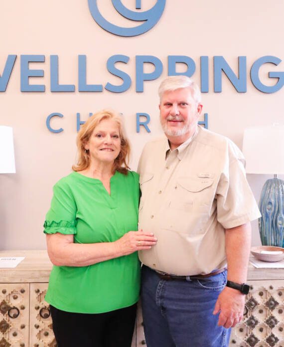 Couple smiling in front of church sign.
