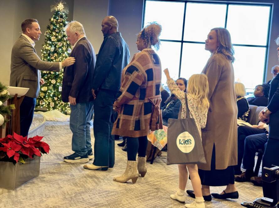 People greeting each other near Christmas tree.