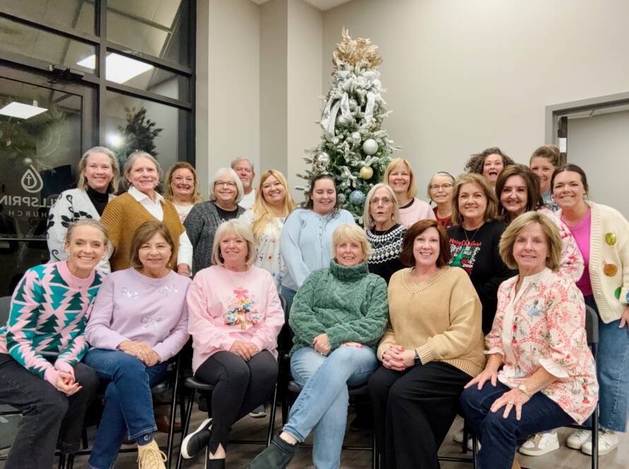 Group of women posing near Christmas tree.