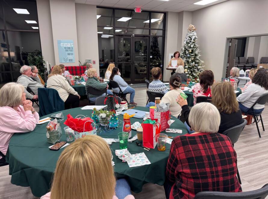 Group gathering around decorated Christmas tree indoors.
