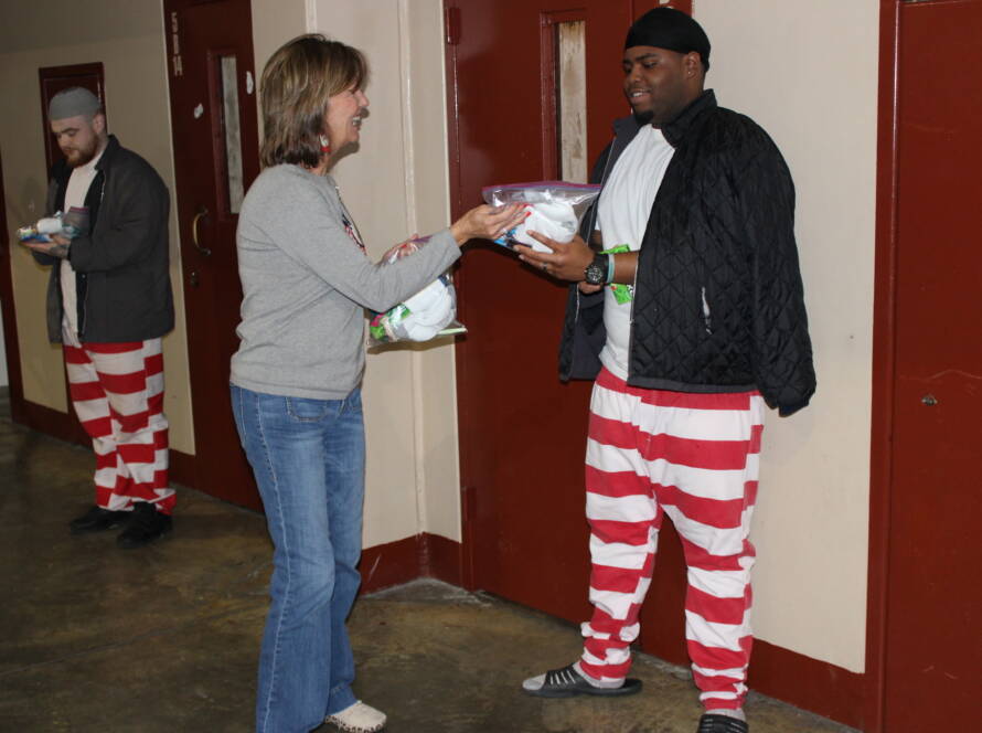Woman handing items to people in uniforms.