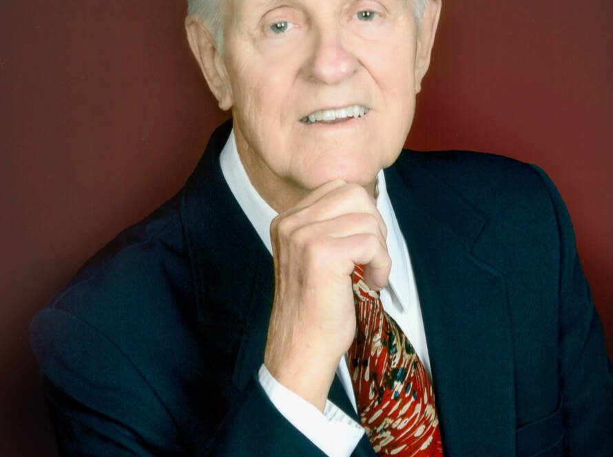 Elderly man in suit with red tie.