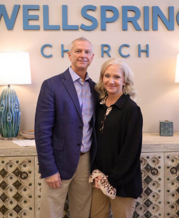 Couple standing in front of Wellspring Church sign.