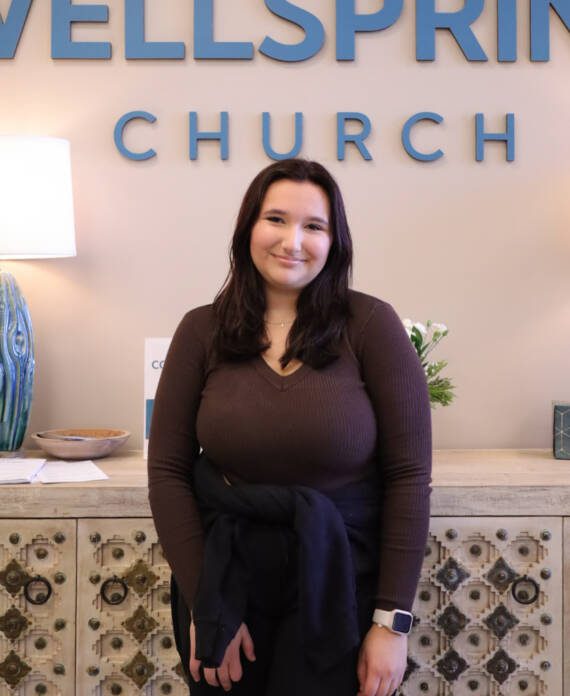 Woman smiling at Wellspring Church entrance.