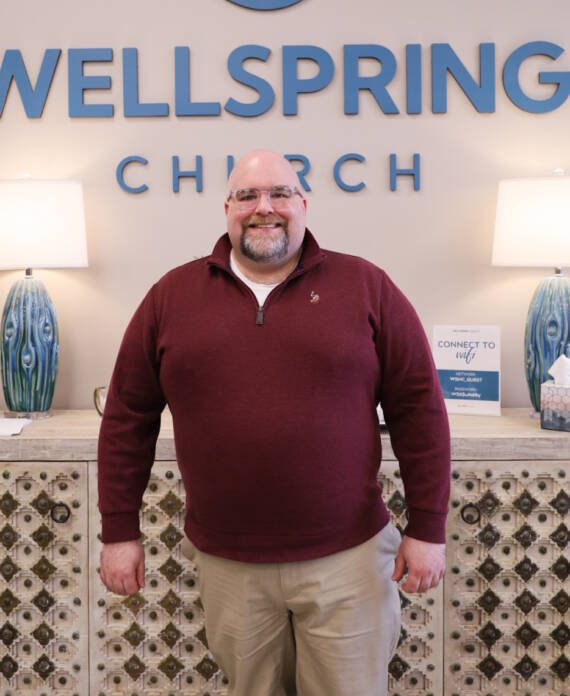 Smiling man standing in Wellspring Church lobby.