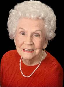 Elderly woman smiling, wearing red sweater.
