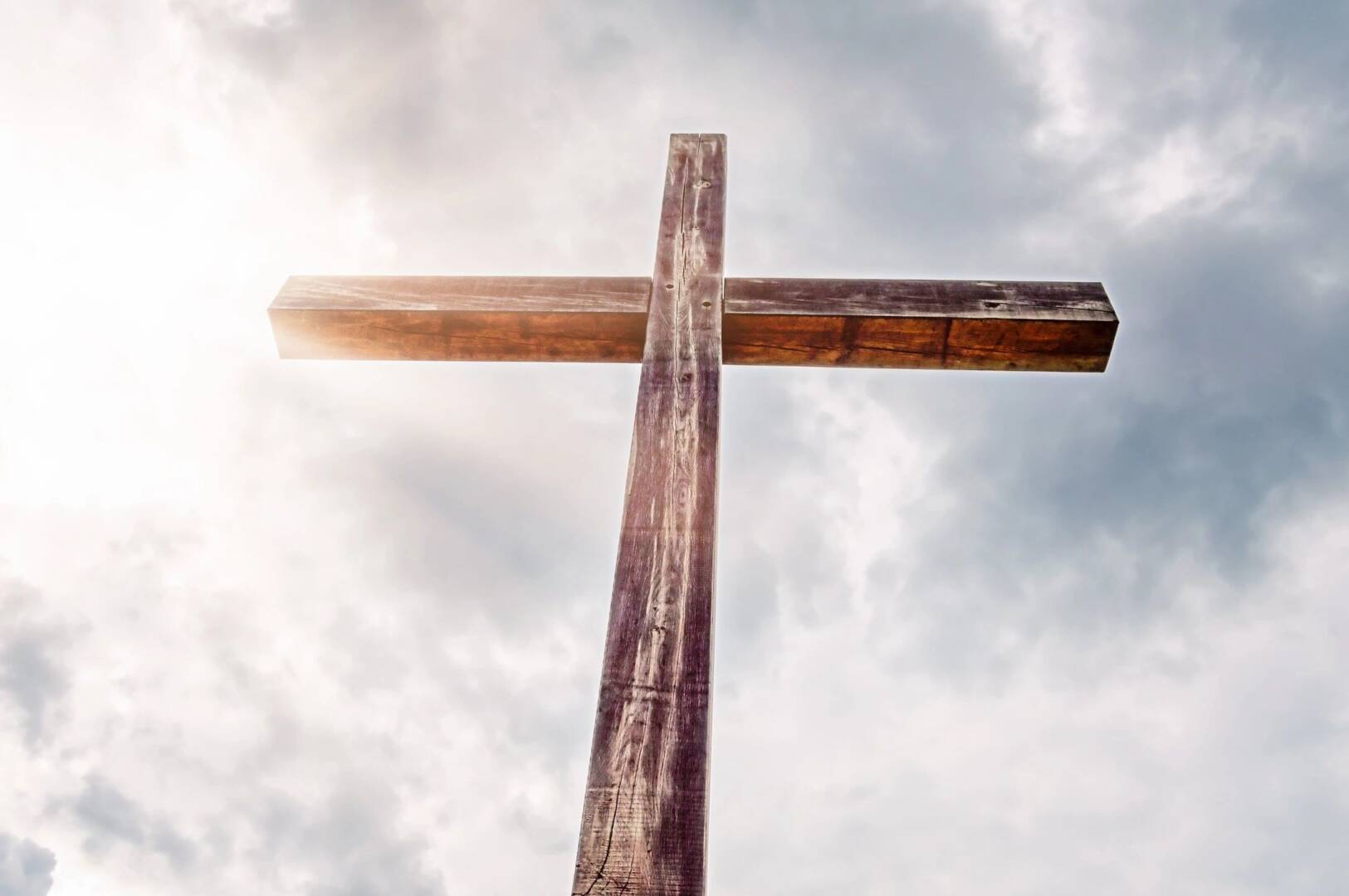 Wooden cross against a cloudy sky.