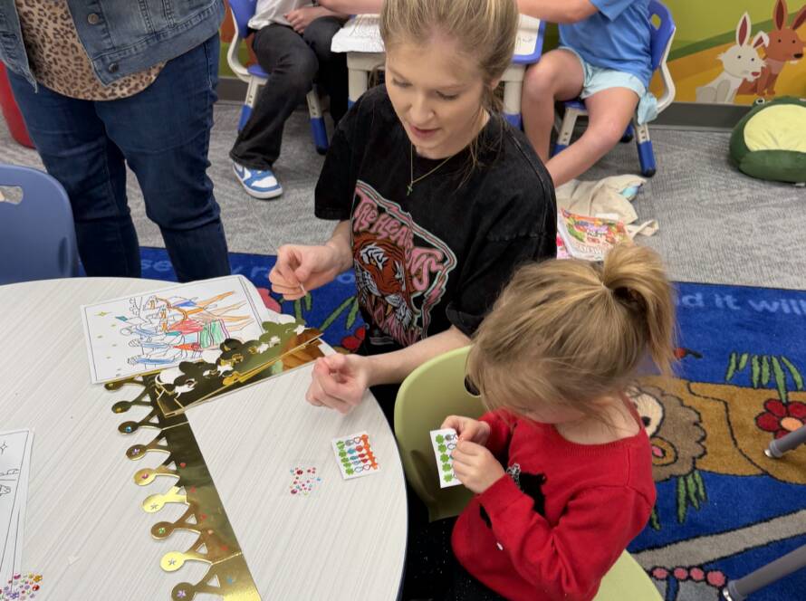 Adults and children crafting in playroom.