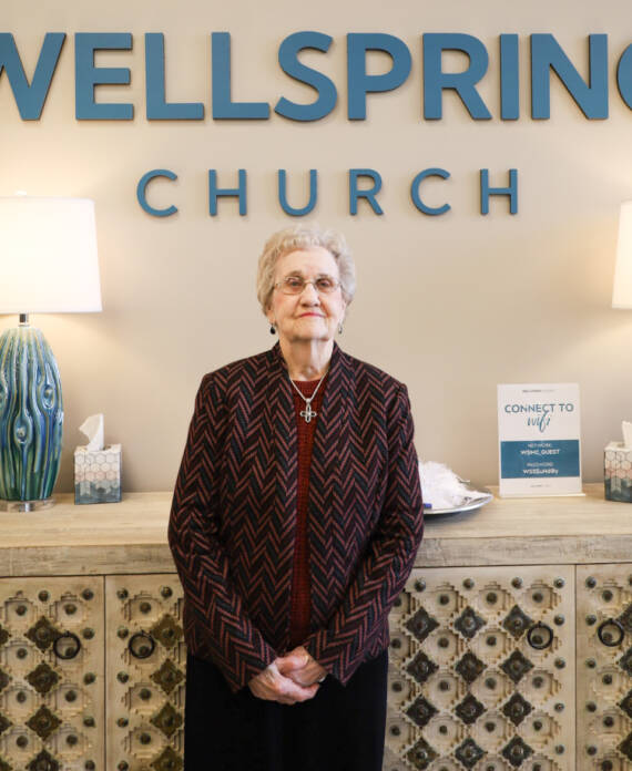 Elderly woman standing in church lobby.