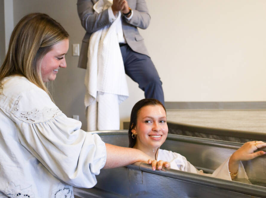 Woman assisting another in baptismal pool.