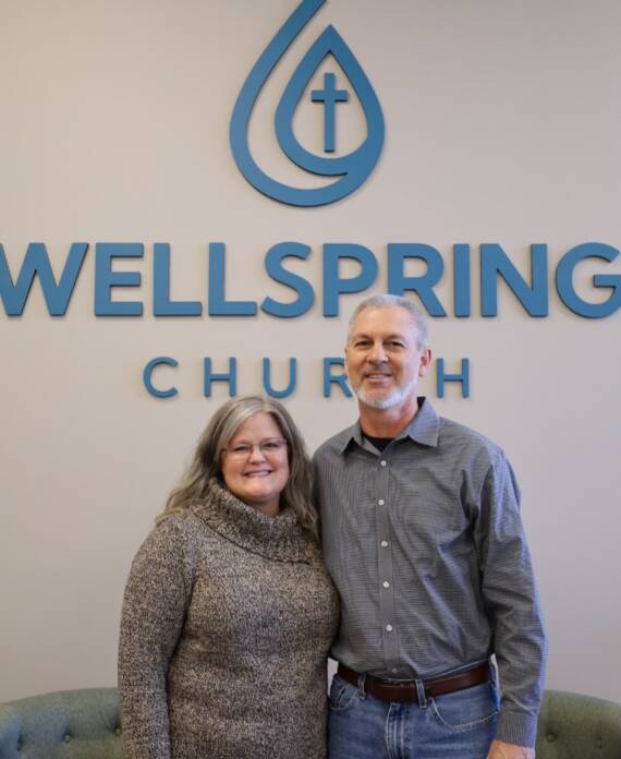 Couple standing in front of church sign.