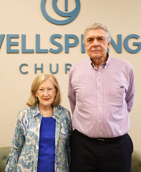 Two people standing in front of sign.