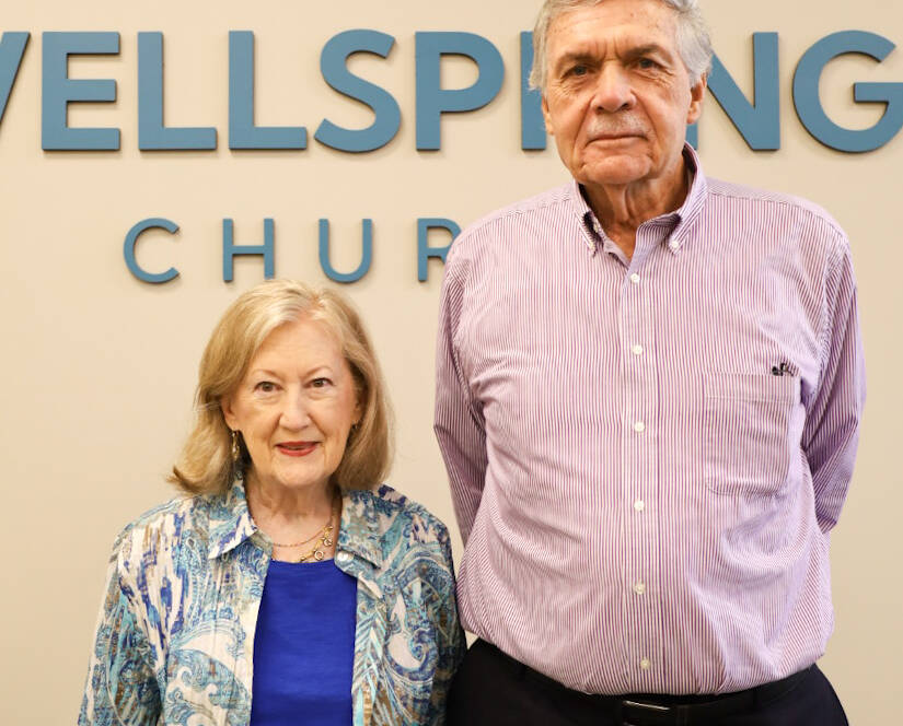 Two people standing in front of sign.