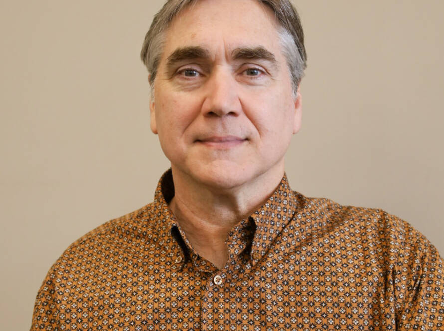 Middle-aged man wearing patterned shirt, beige background