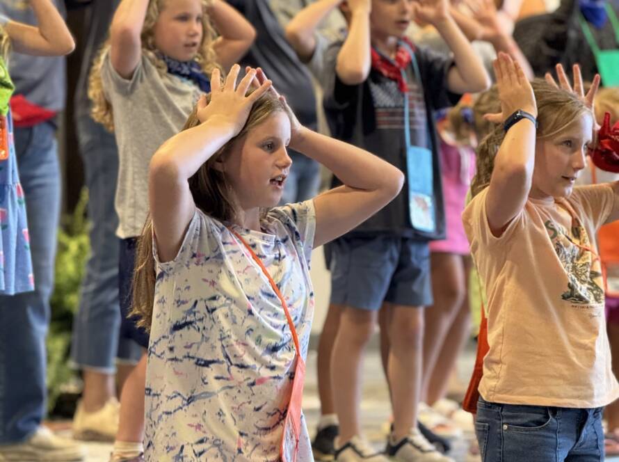 Children on stage with hands on heads