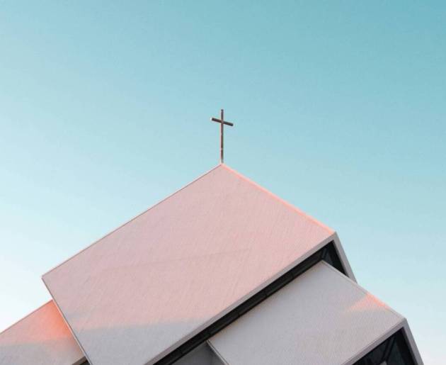 White church with cross against blue sky.